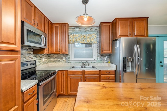 kitchen featuring appliances with stainless steel finishes, tasteful backsplash, sink, butcher block countertops, and hanging light fixtures