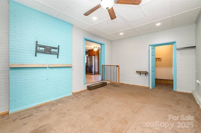 spare room featuring carpet and brick wall