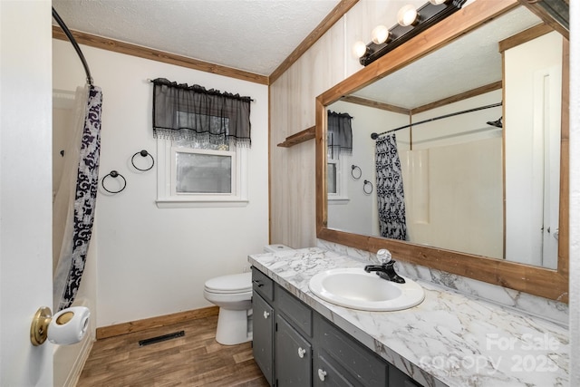 bathroom featuring vanity, a textured ceiling, crown molding, hardwood / wood-style floors, and toilet