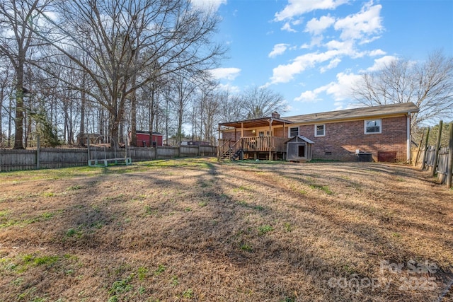 view of yard with a trampoline and a wooden deck