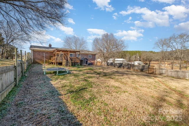 view of yard with a trampoline and a wooden deck