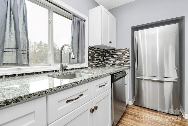 kitchen with light stone counters, sink, white cabinets, and appliances with stainless steel finishes