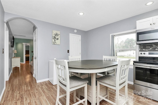 dining space with light hardwood / wood-style floors and a textured ceiling