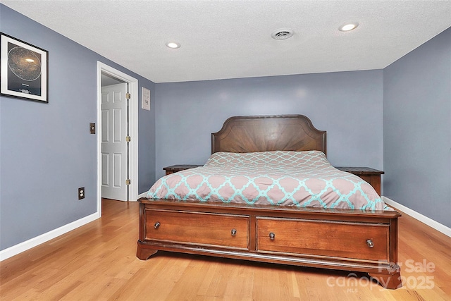 bedroom with a textured ceiling and light hardwood / wood-style flooring