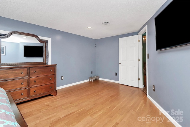 unfurnished bedroom with light wood-type flooring and a textured ceiling