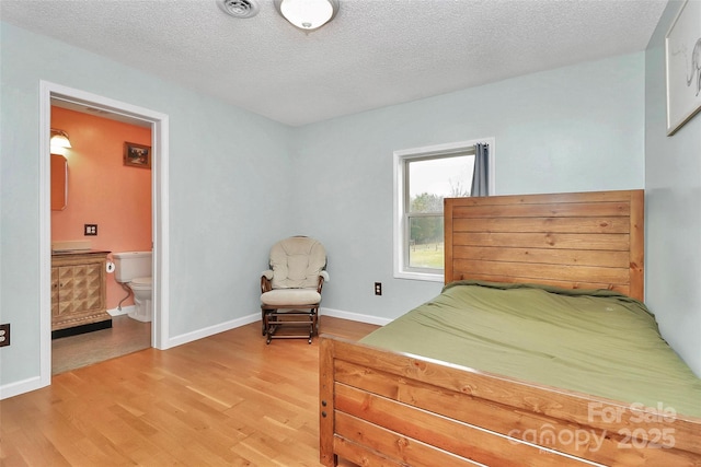 bedroom featuring connected bathroom, hardwood / wood-style floors, and a textured ceiling