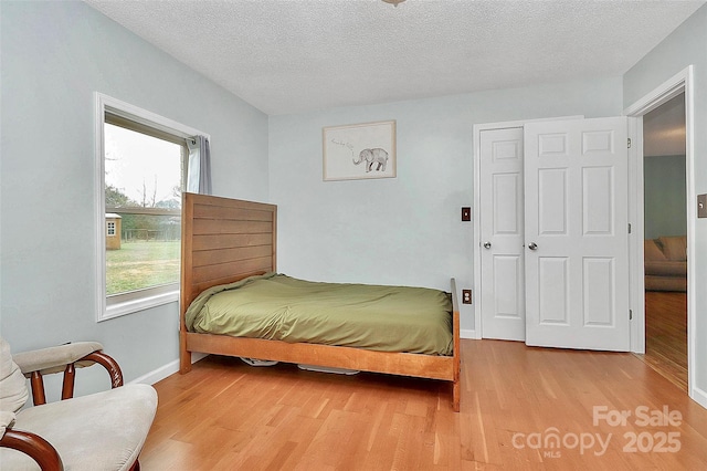 bedroom featuring a textured ceiling, light wood-type flooring, and a closet