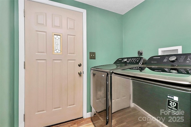 clothes washing area with washer and dryer, a textured ceiling, and light hardwood / wood-style flooring