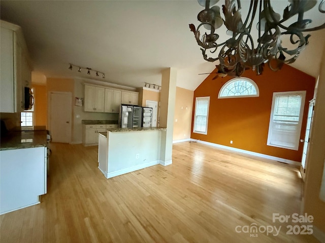 kitchen featuring stainless steel refrigerator, lofted ceiling, track lighting, white cabinets, and light wood-type flooring