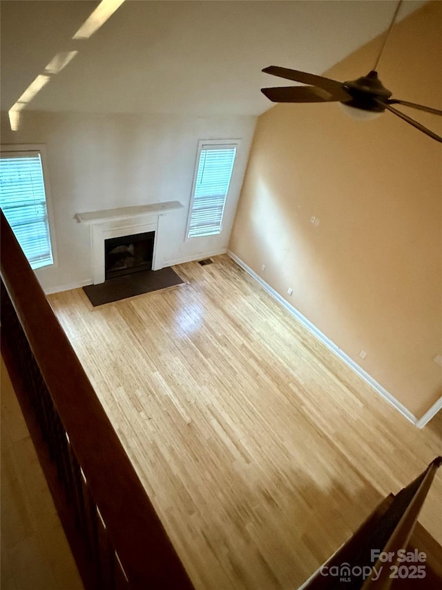 unfurnished living room with a healthy amount of sunlight, ceiling fan, and light hardwood / wood-style floors