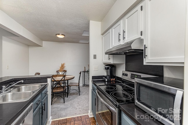 kitchen with stainless steel appliances, dark countertops, white cabinetry, a sink, and under cabinet range hood