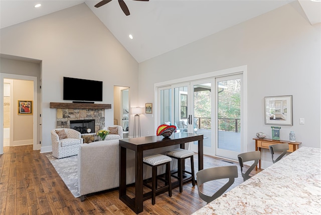 living room with ceiling fan, a fireplace, dark hardwood / wood-style flooring, and high vaulted ceiling