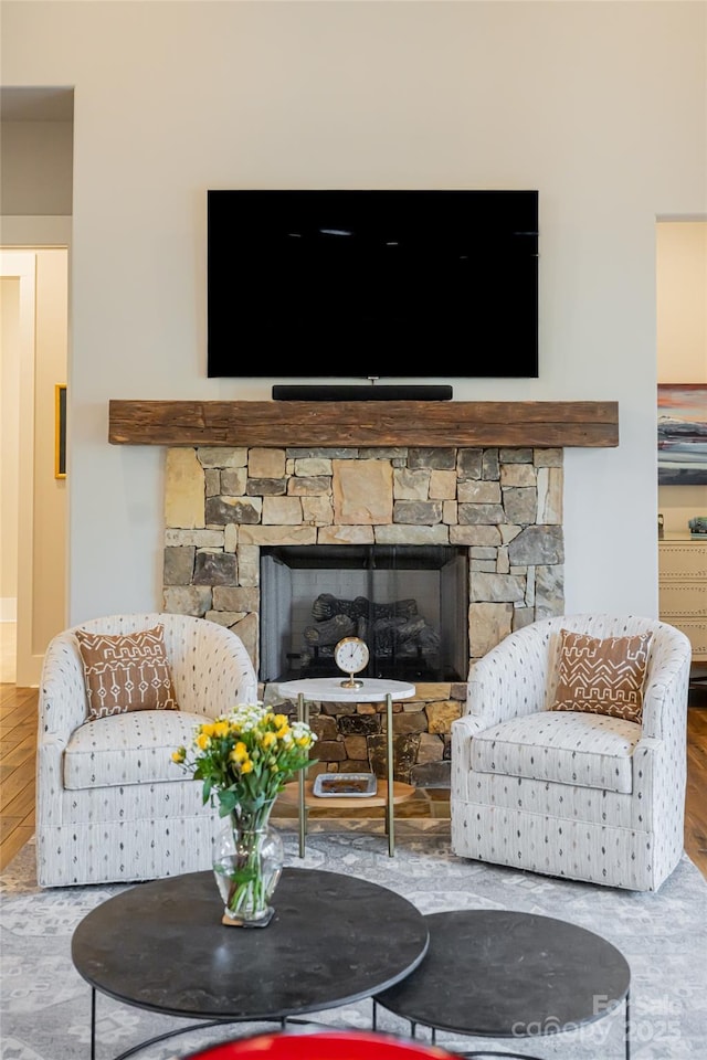 living room with wood-type flooring and a stone fireplace