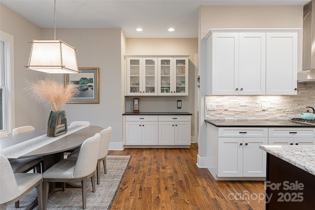 kitchen featuring dark hardwood / wood-style flooring, backsplash, decorative light fixtures, and white cabinets