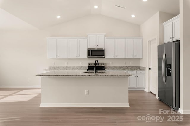 kitchen with white cabinetry, an island with sink, light stone counters, and appliances with stainless steel finishes