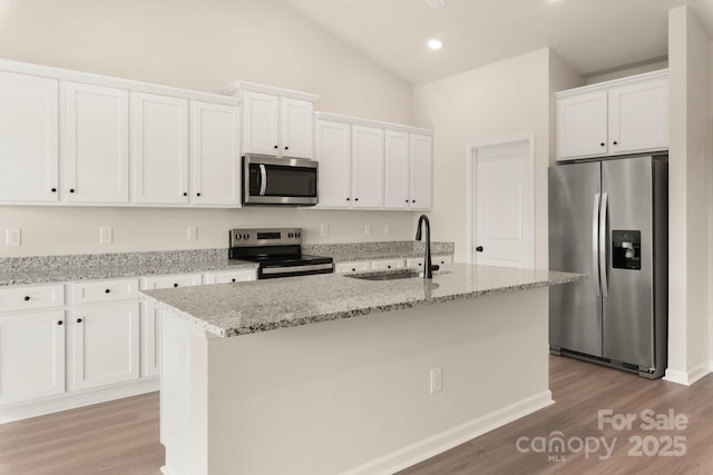 kitchen with white cabinets, stainless steel appliances, a center island with sink, and sink