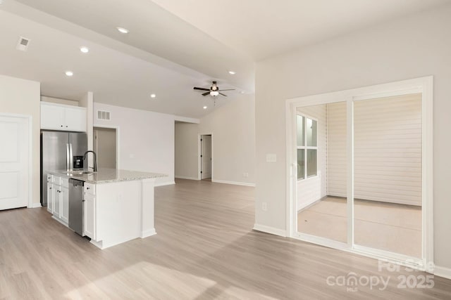 kitchen featuring ceiling fan, stainless steel appliances, light stone counters, white cabinets, and light wood-type flooring