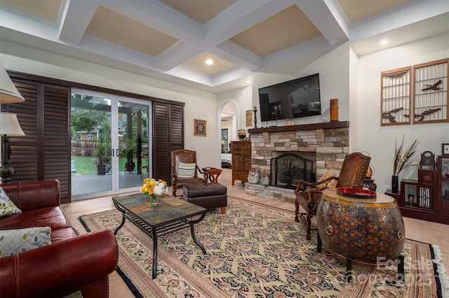 living room featuring beam ceiling, a stone fireplace, and coffered ceiling