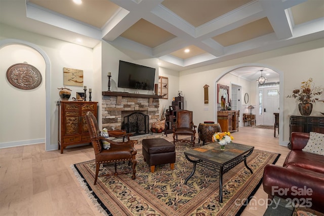 living room featuring beam ceiling, coffered ceiling, a notable chandelier, light hardwood / wood-style floors, and a fireplace