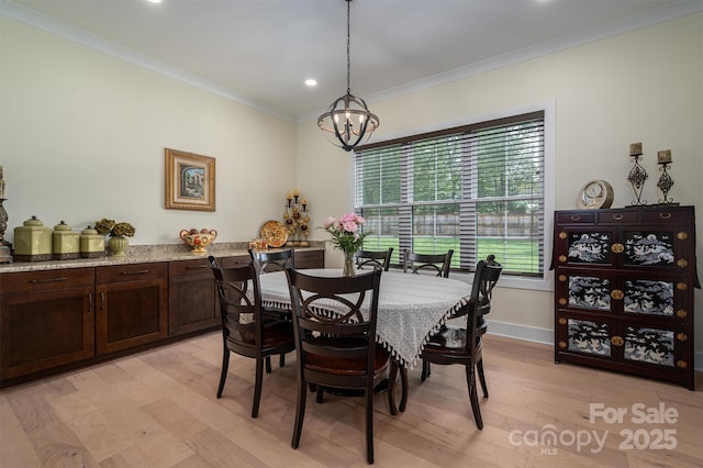 dining area with an inviting chandelier, light hardwood / wood-style flooring, and crown molding