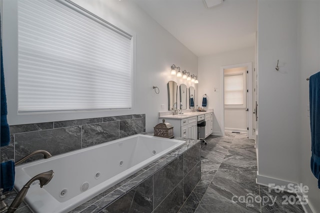 bathroom featuring vanity, vaulted ceiling, and tiled tub