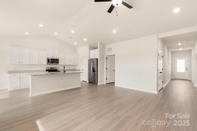 kitchen with white cabinets, light stone countertops, an island with sink, light hardwood / wood-style floors, and stainless steel appliances