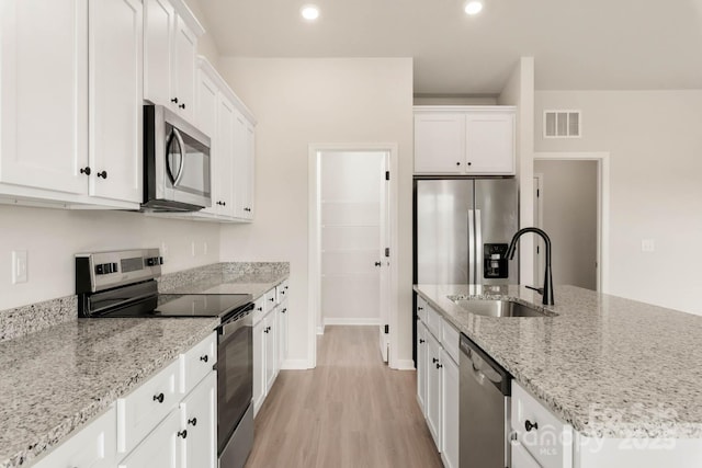 kitchen featuring white cabinets, appliances with stainless steel finishes, light stone counters, and sink