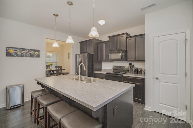 kitchen featuring black appliances, sink, a kitchen island with sink, and decorative light fixtures