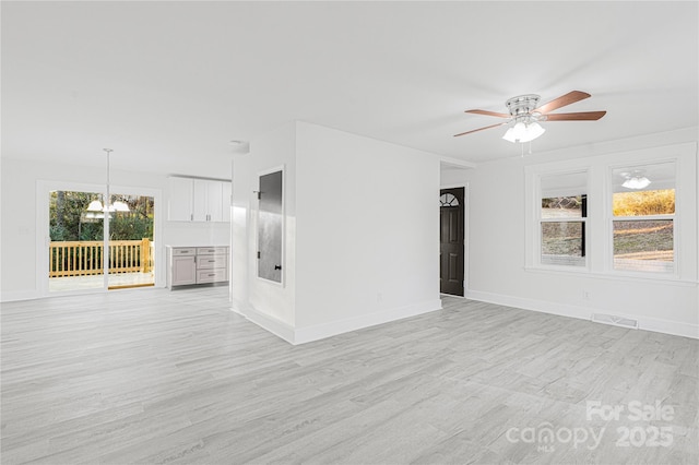 spare room featuring light hardwood / wood-style floors and ceiling fan with notable chandelier