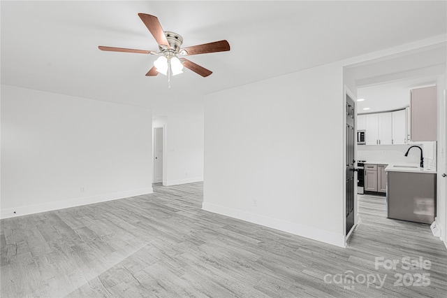 unfurnished living room featuring ceiling fan, sink, and light hardwood / wood-style flooring