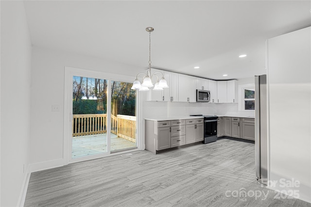 kitchen featuring gray cabinetry, hanging light fixtures, tasteful backsplash, light hardwood / wood-style floors, and stainless steel appliances