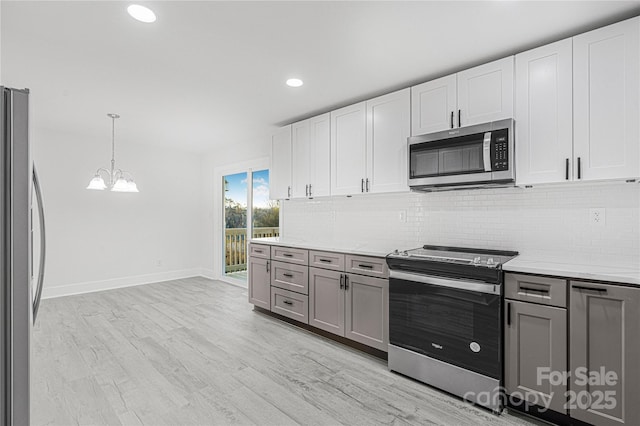 kitchen with white cabinetry, hanging light fixtures, backsplash, gray cabinets, and appliances with stainless steel finishes