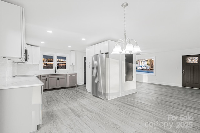 kitchen featuring tasteful backsplash, stainless steel appliances, sink, decorative light fixtures, and white cabinets