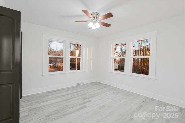 empty room with light wood-type flooring, a wealth of natural light, and ceiling fan