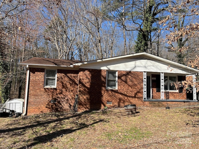 view of property exterior with crawl space, a storage shed, and brick siding