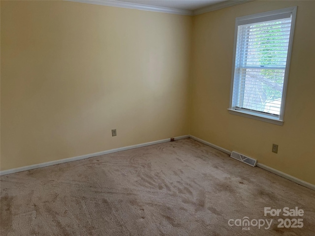 carpeted empty room featuring crown molding, baseboards, and visible vents