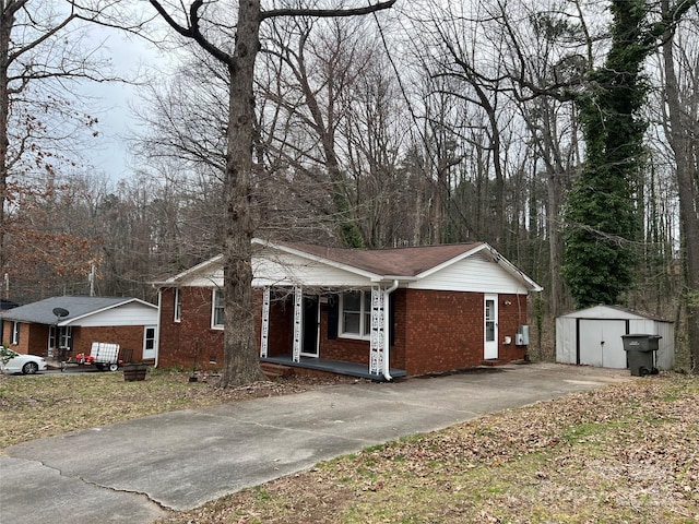 view of front of property with brick siding, covered porch, an outdoor structure, and a storage shed