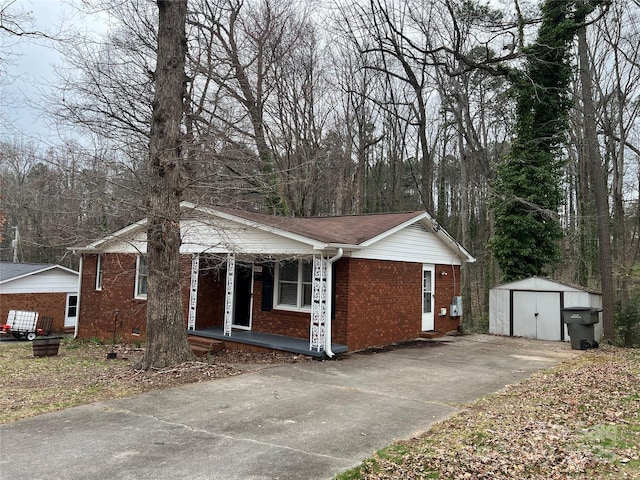 view of front of house featuring brick siding, a porch, and an outdoor structure