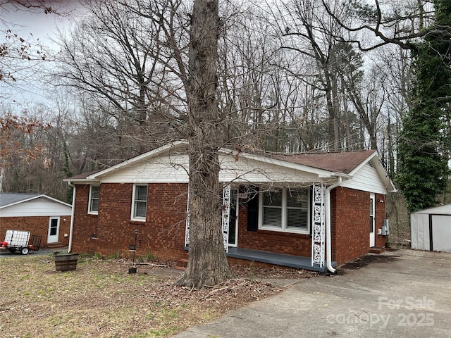 exterior space featuring a porch, brick siding, and an outdoor structure