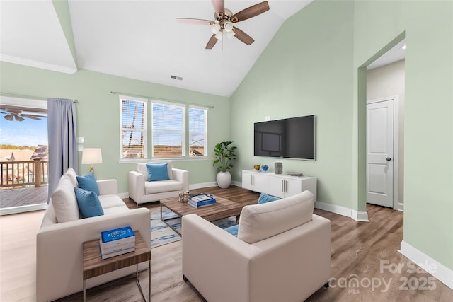 living room with high vaulted ceiling, a healthy amount of sunlight, and light hardwood / wood-style flooring