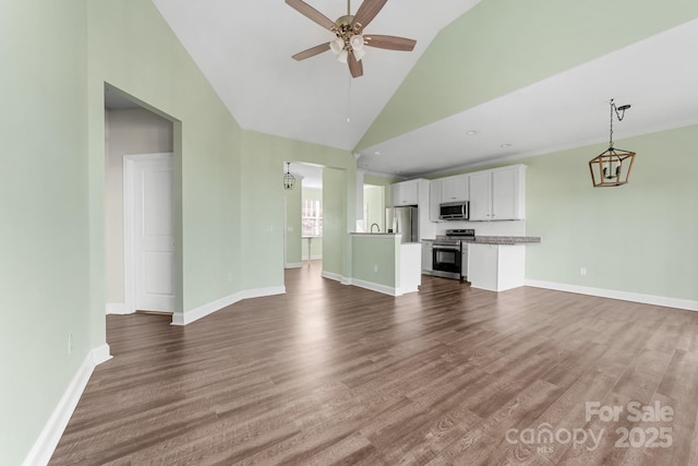 unfurnished living room with vaulted ceiling, dark wood-type flooring, and ceiling fan with notable chandelier