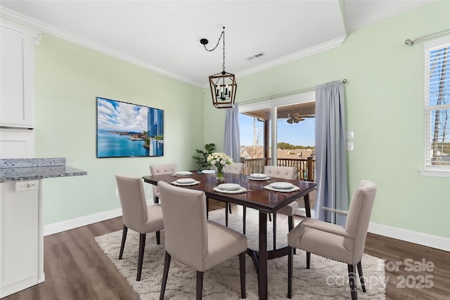 dining space with an inviting chandelier, crown molding, and dark hardwood / wood-style floors