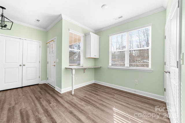 foyer entrance featuring hardwood / wood-style flooring, crown molding, and a notable chandelier