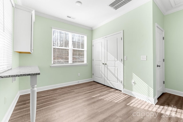 interior space with a closet, crown molding, and light wood-type flooring