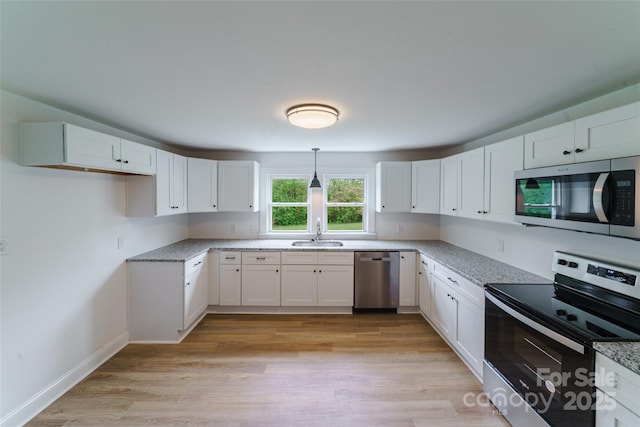 kitchen with white cabinets, appliances with stainless steel finishes, hanging light fixtures, and sink