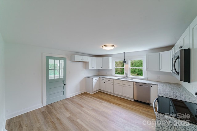 kitchen with hanging light fixtures, light stone counters, a wall unit AC, white cabinets, and appliances with stainless steel finishes