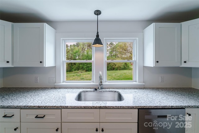 kitchen featuring white cabinets, light stone counters, stainless steel dishwasher, and sink