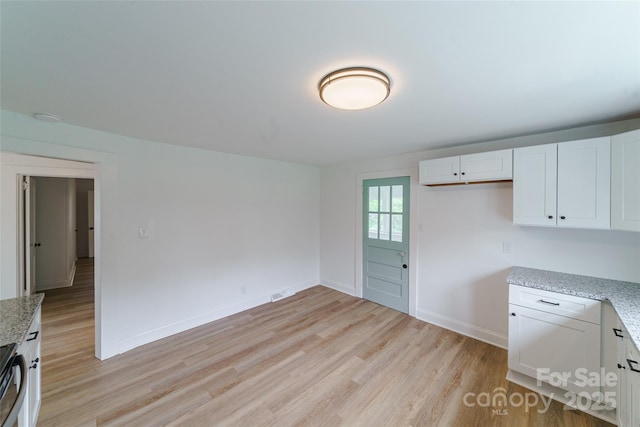 kitchen with light stone countertops, white cabinets, and light hardwood / wood-style floors