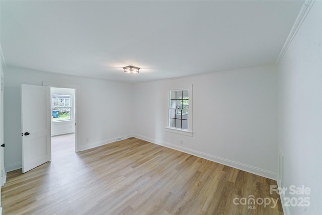 empty room with light hardwood / wood-style flooring and crown molding