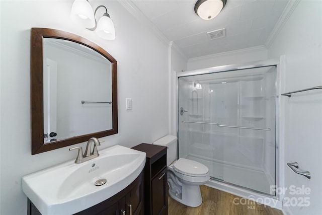 bathroom with toilet, wood-type flooring, a shower with shower door, and ornamental molding